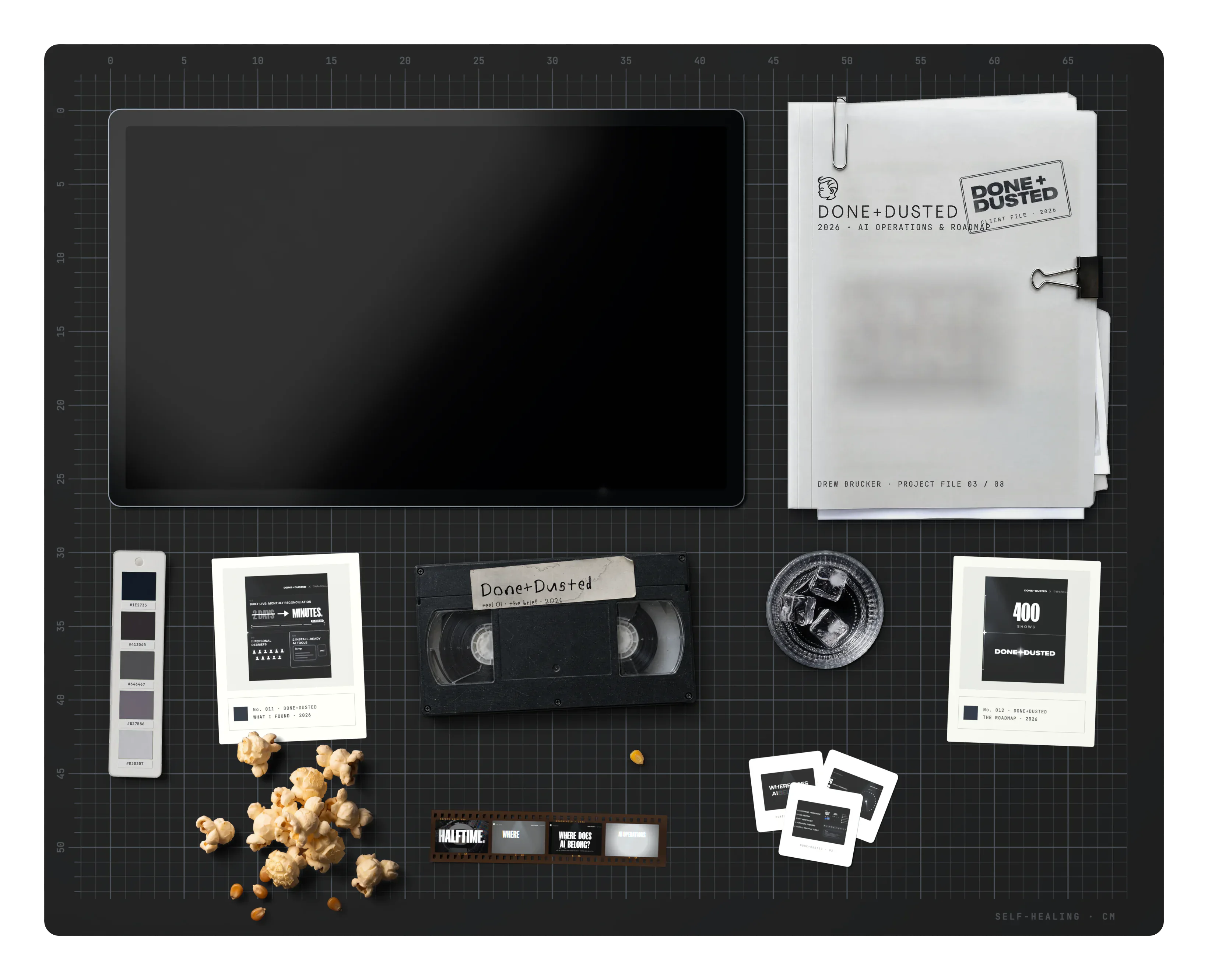 Done+Dusted on the desk: the project file, the brand swatch, archive cards, a VHS tape, a film strip, a glass of water, slides and spilled popcorn
