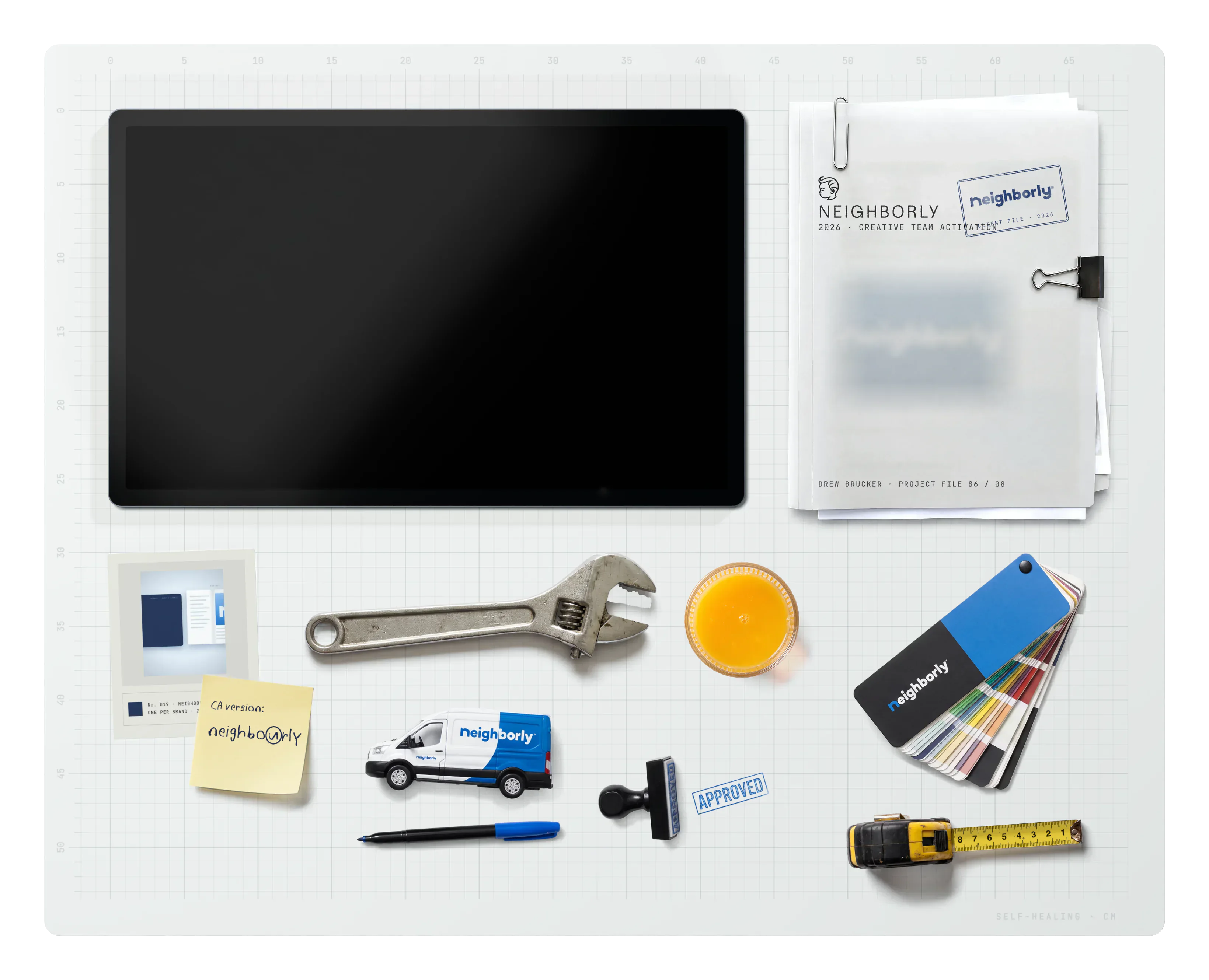 Neighborly on the desk: the project file, archive cards, a sticky note, a pipe wrench, a toy Neighborly van, a marker, a glass of orange juice, an APPROVED rubber stamp, a Neighborly fan deck and a tape measure