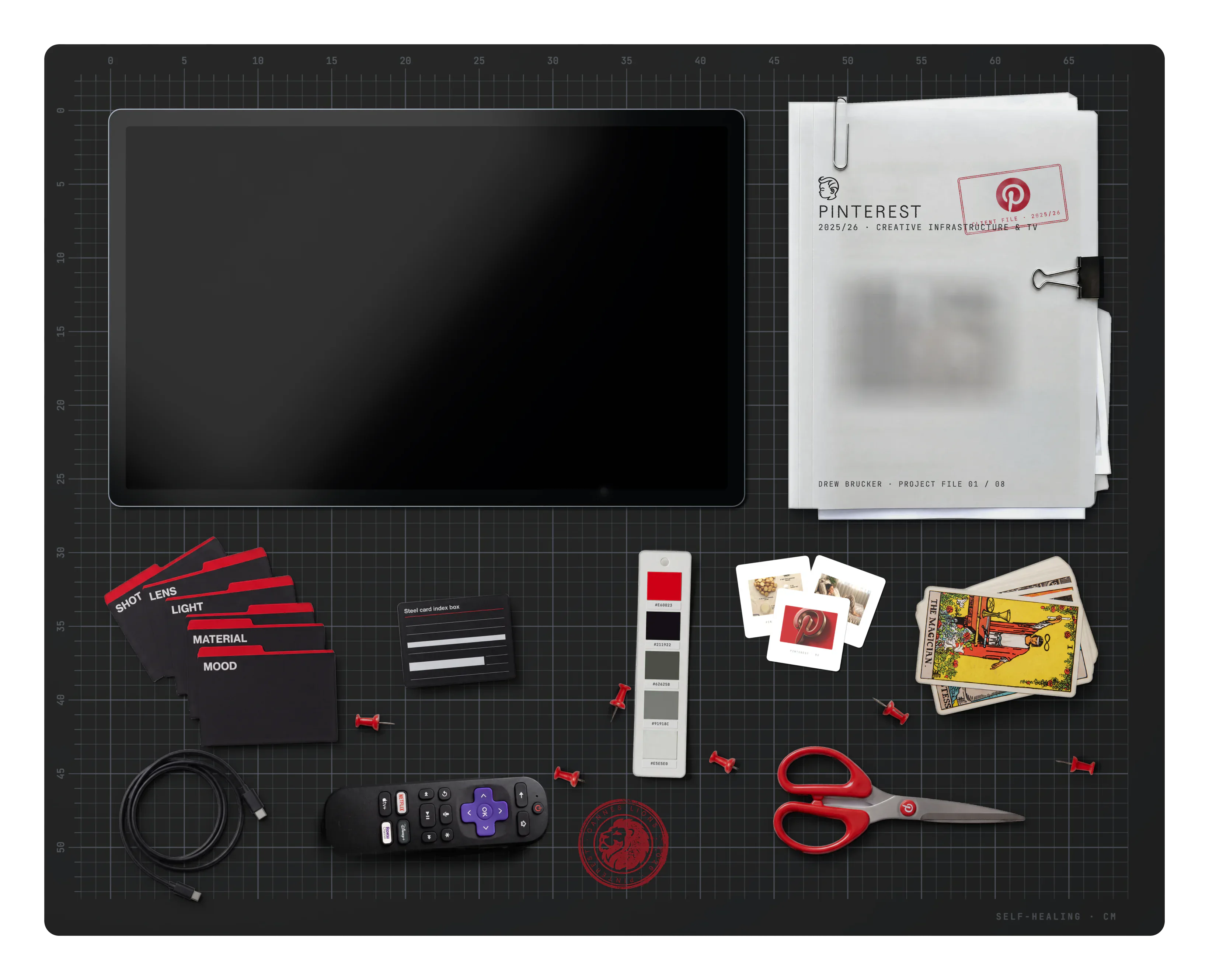 Pinterest on the desk: the project file, slides, the brand swatch, a Cannes Lions stamp, prompt-section index dividers, a USB-C cable, a tarot deck, an index-box label card, a Roku remote, scissors and push pins