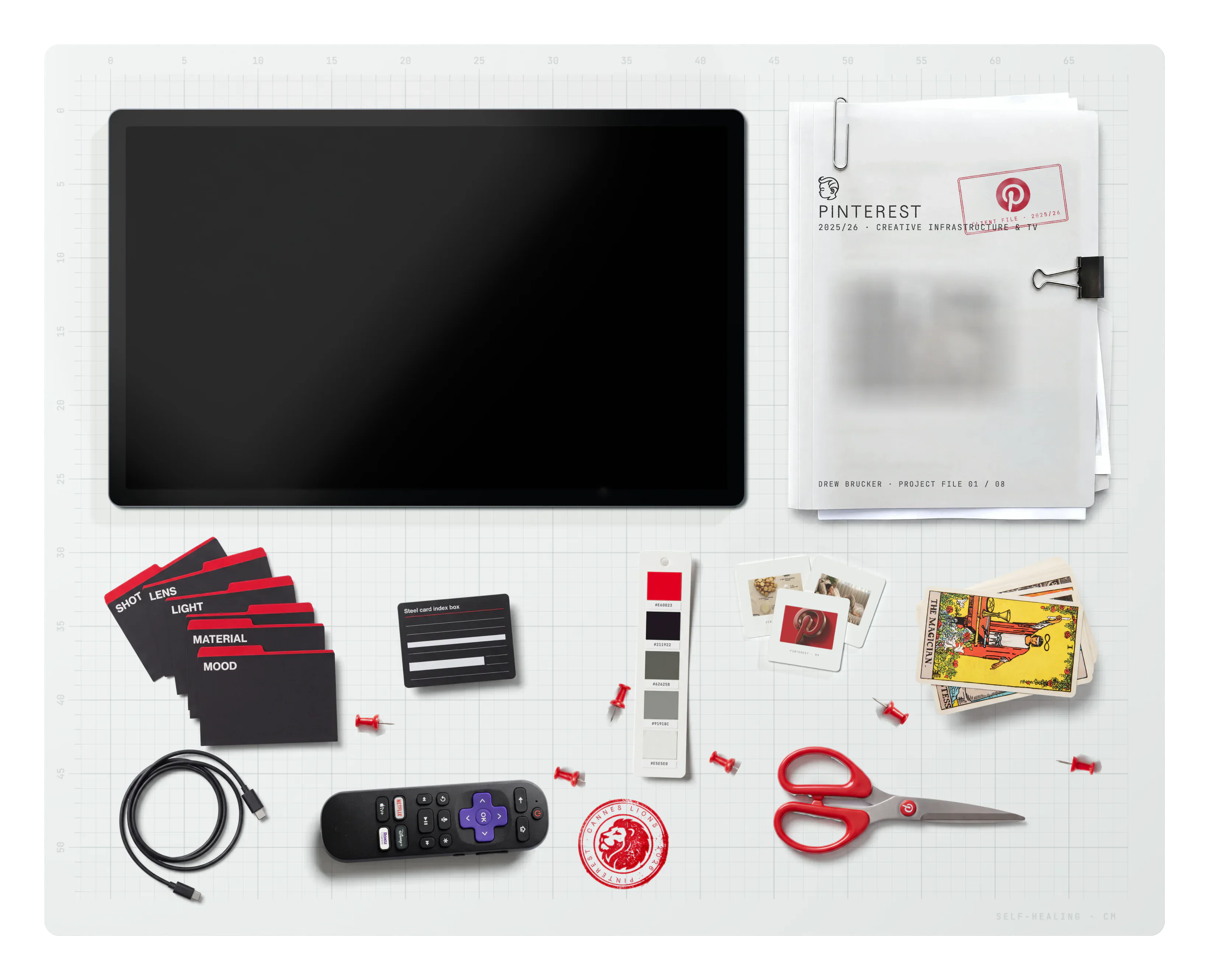 Pinterest on the desk: the project file, slides, the brand swatch, a Cannes Lions stamp, prompt-section index dividers, a USB-C cable, a tarot deck, an index-box label card, a Roku remote, scissors and push pins